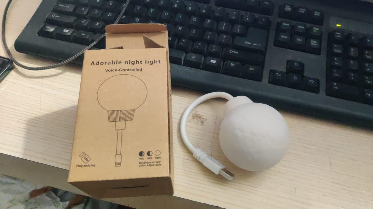 White night light with packaging on a desk next to a keyboard