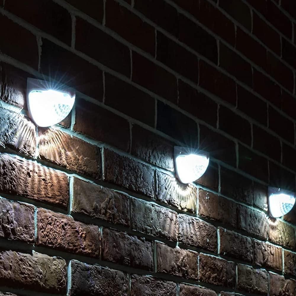 Three outdoor wall lights mounted on a brick wall at night.