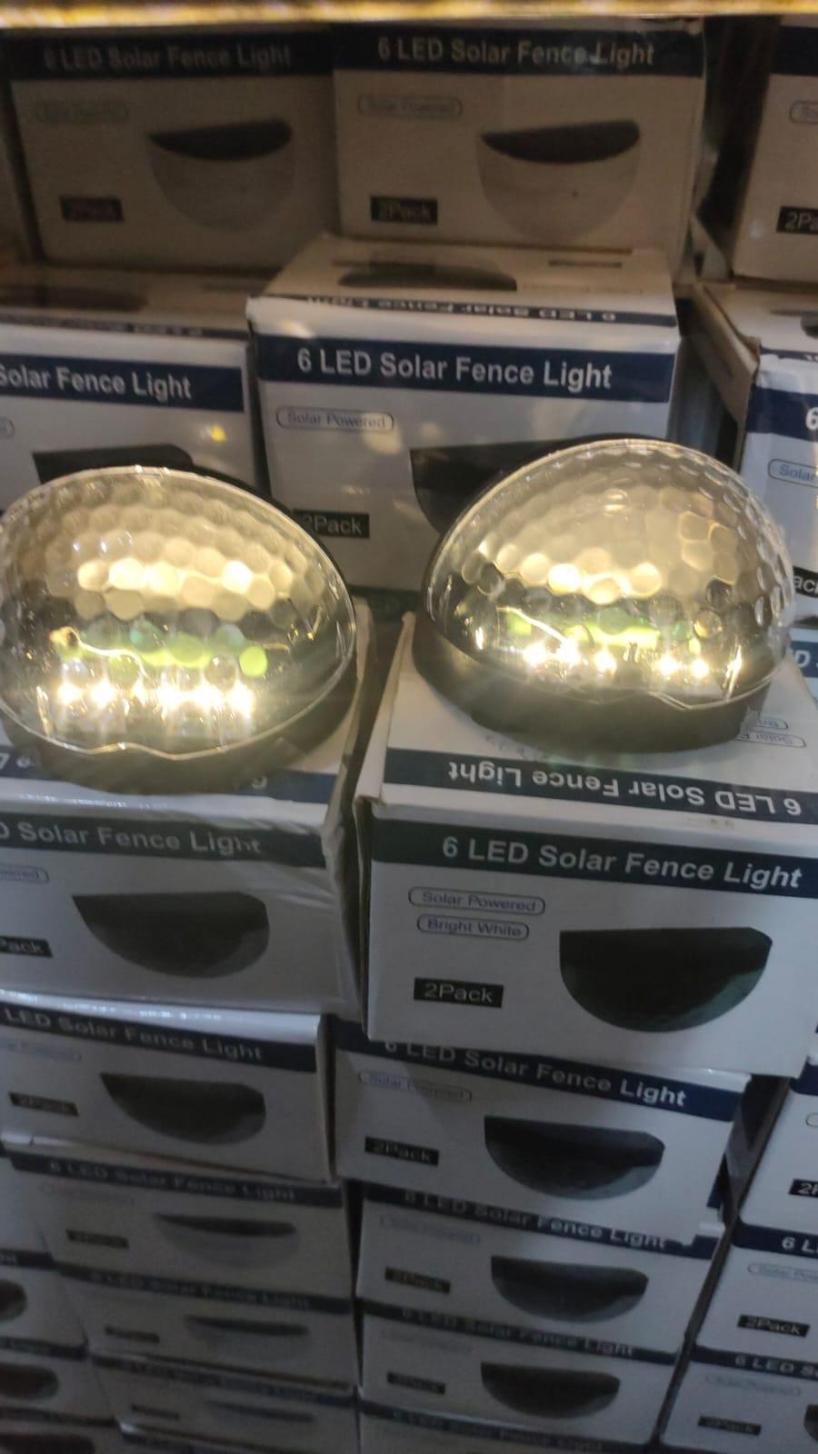Stacks of 6 LED Solar Fence Lights in boxes on a shelf.